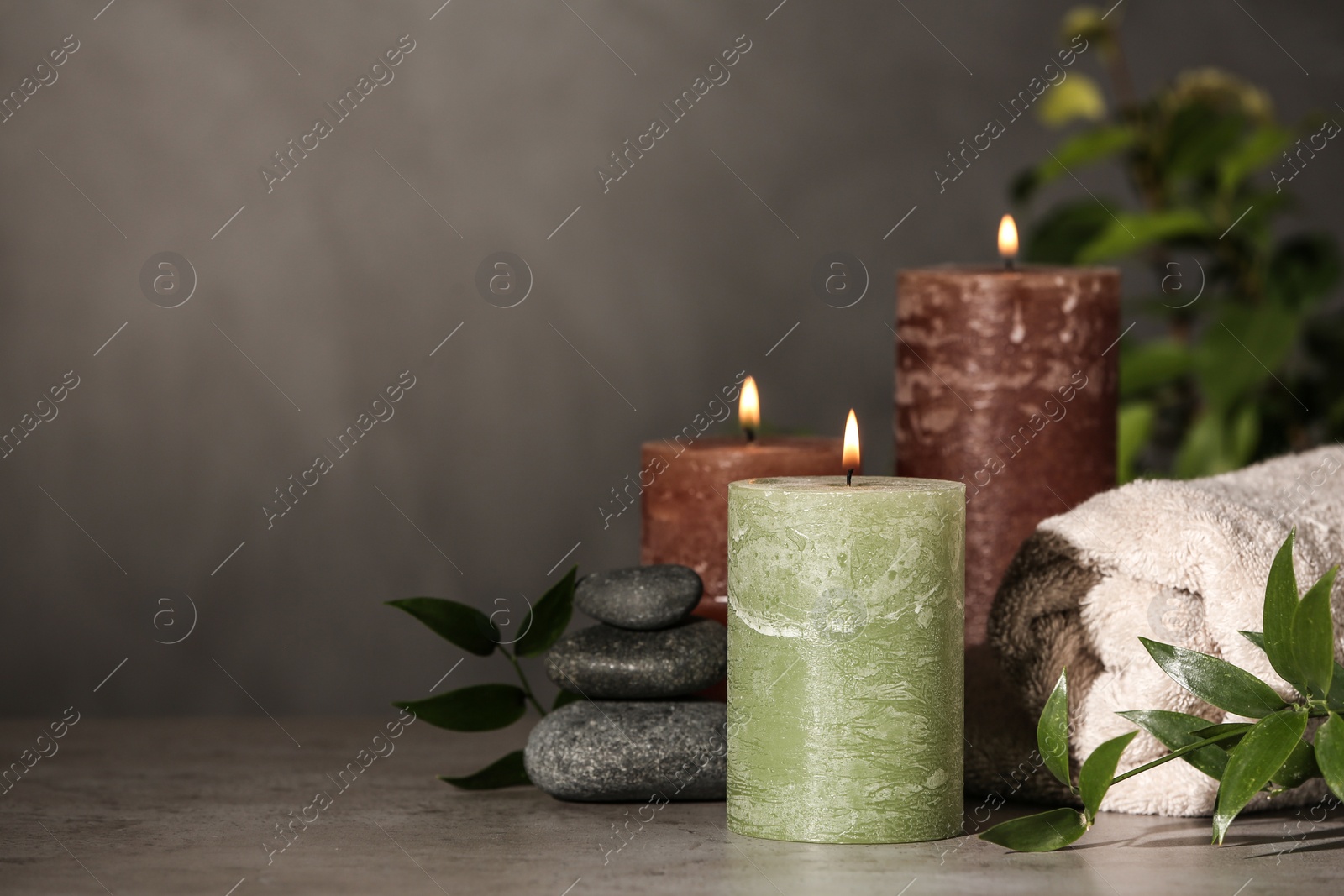 Photo of Composition with candles and spa stones on grey table. Space for text