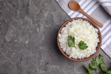Photo of Bowl with tasty cooked rice on grey table, flat lay. Space for text