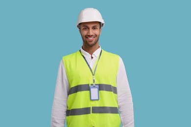 Engineer with hard hat and badge on light blue background