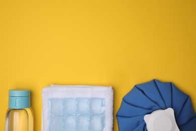 Photo of Bottle of water, ice pack, cold compress and towel on yellow background, flat lay with space for text. Heat stroke treatment