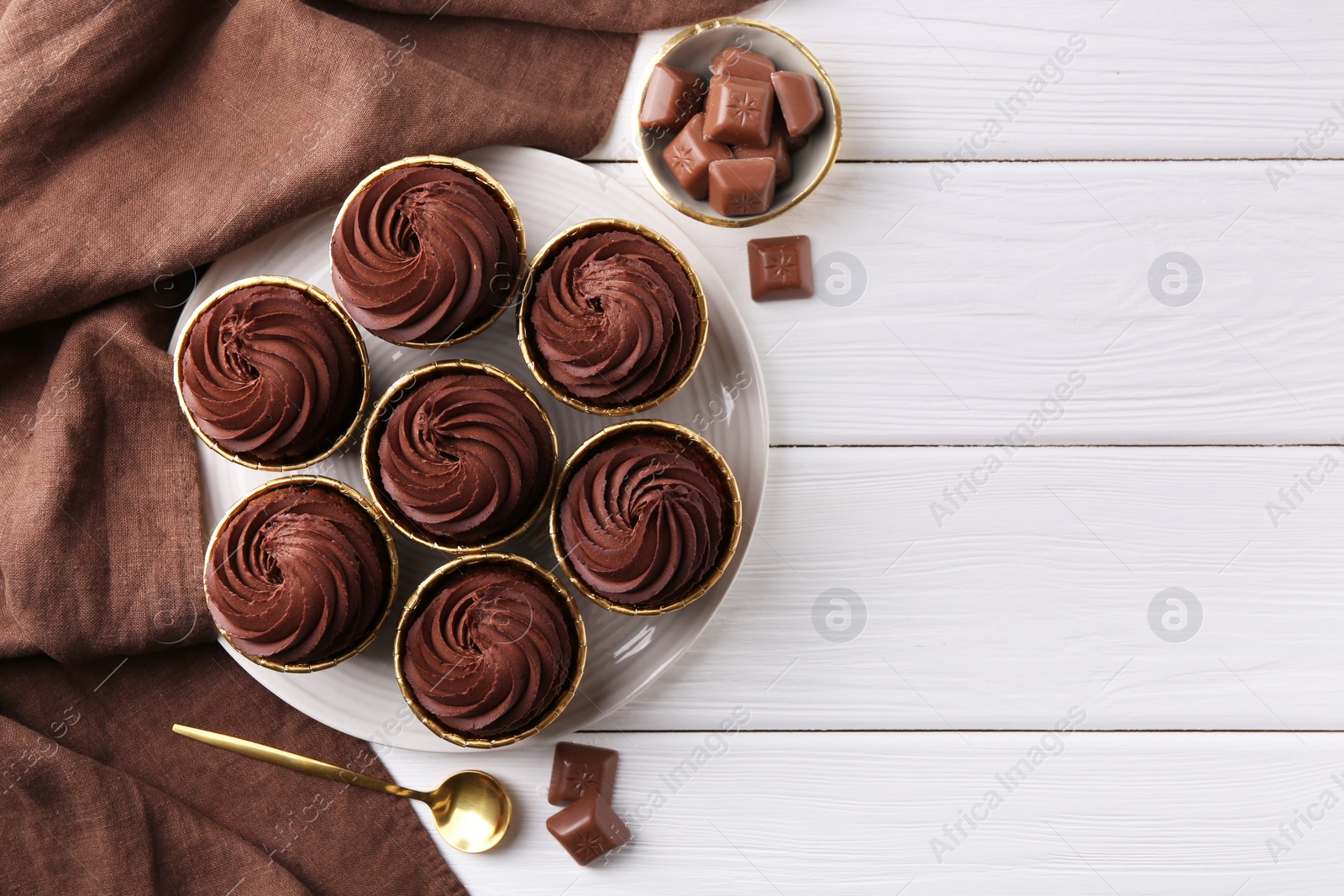 Photo of Delicious cupcake and chocolate pieces on white wooden table, flat lay. Space for text