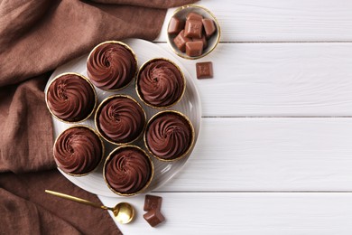 Photo of Delicious cupcake and chocolate pieces on white wooden table, flat lay. Space for text