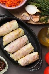Photo of Uncooked stuffed cabbage rolls and ingredients on grey table, flat lay