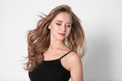 Portrait of young woman with long beautiful hair on light background