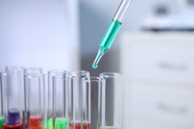 Photo of Dripping sample into test tube in chemistry laboratory, closeup