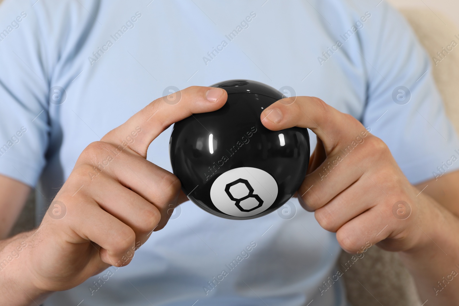 Photo of Man holding magic eight ball indoors, closeup