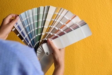 Female interior designer with palette samples on color background, closeup