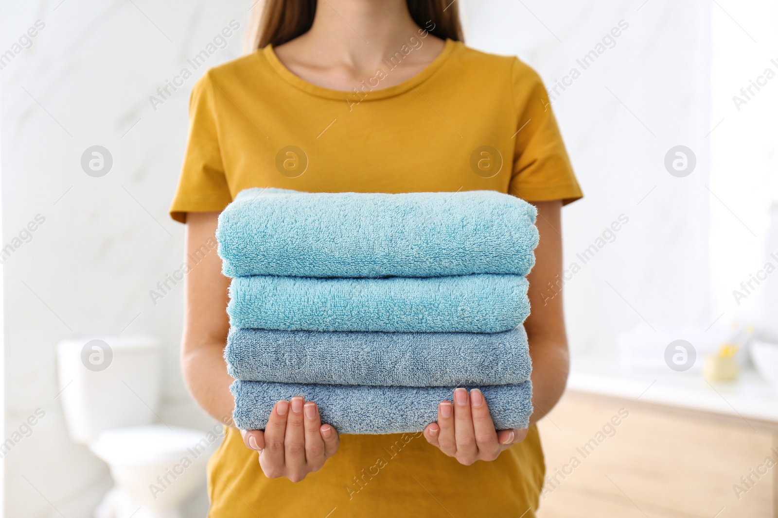 Photo of Woman holding fresh towels in bathroom, closeup