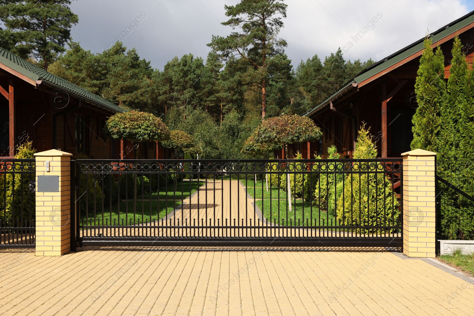 Photo of Closed metal gates near beautiful garden and houses outdoors