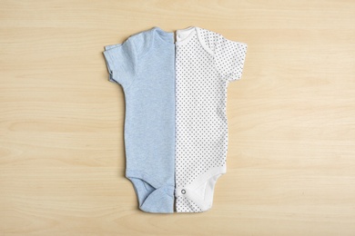 Photo of Different baby bodysuits on wooden background, top view