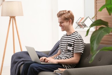 Online learning. Smiling teenage boy typing on laptop at home