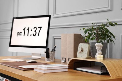 Photo of Stylish workplace with computer, houseplant and stationery on wooden desk near grey wall at home