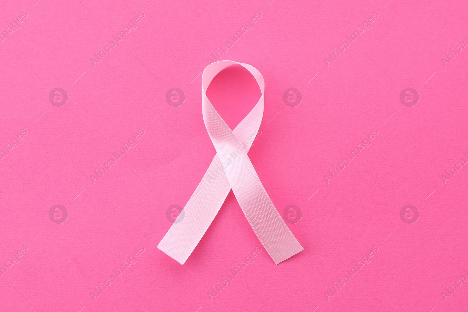 Photo of Awareness ribbon on pink background, top view