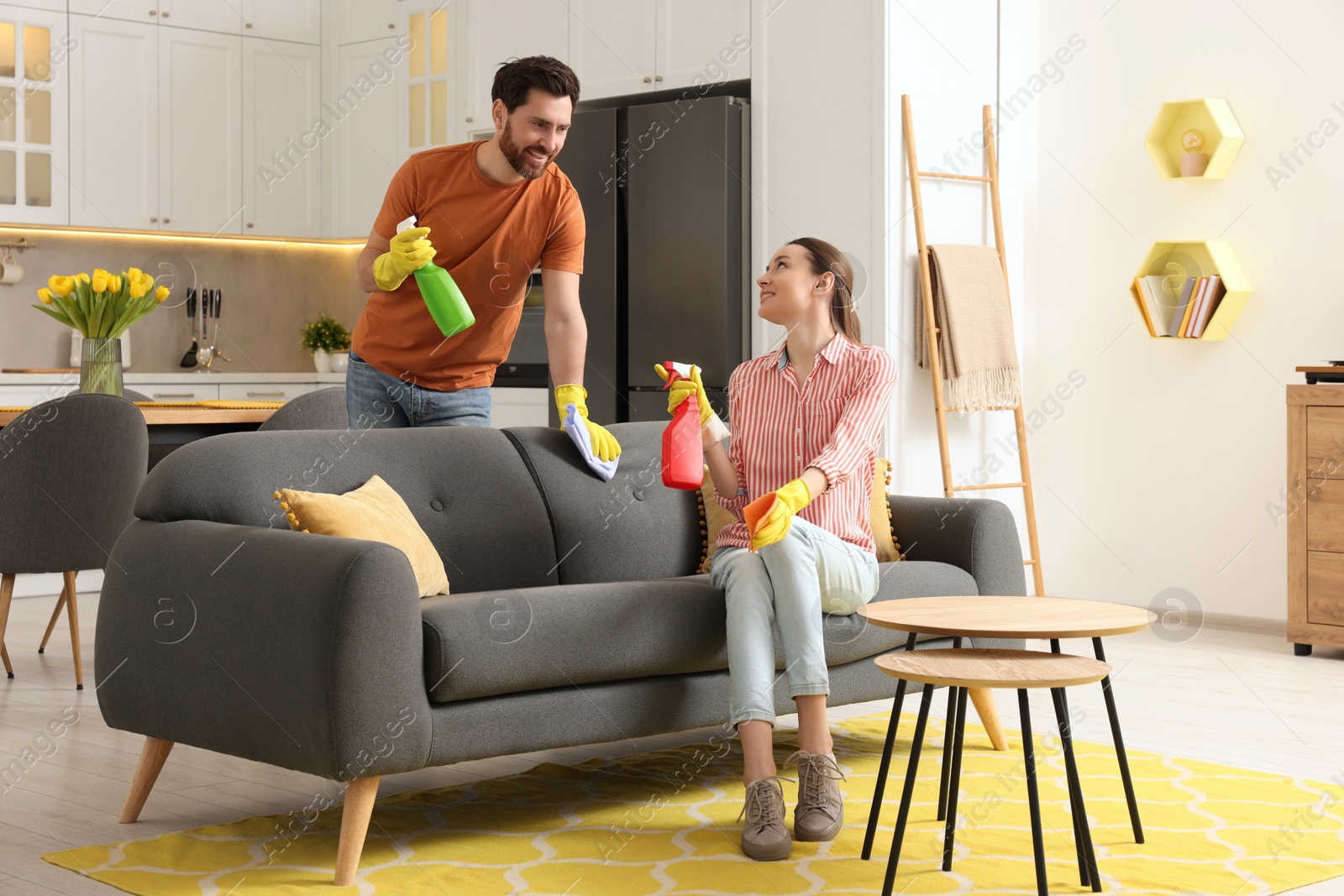 Photo of Spring cleaning. Lovely couple tidying up living room and kitchen together