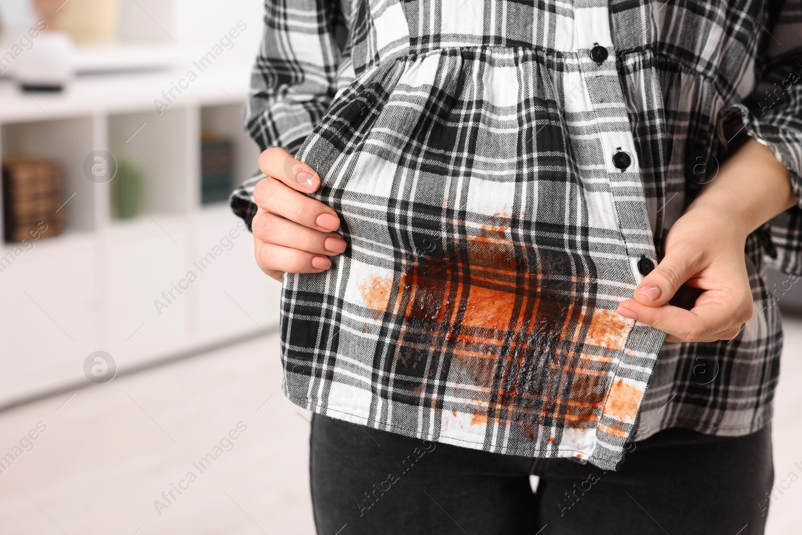 Photo of Woman showing stain from sauce on her shirt against blurred background, closeup. Space for text