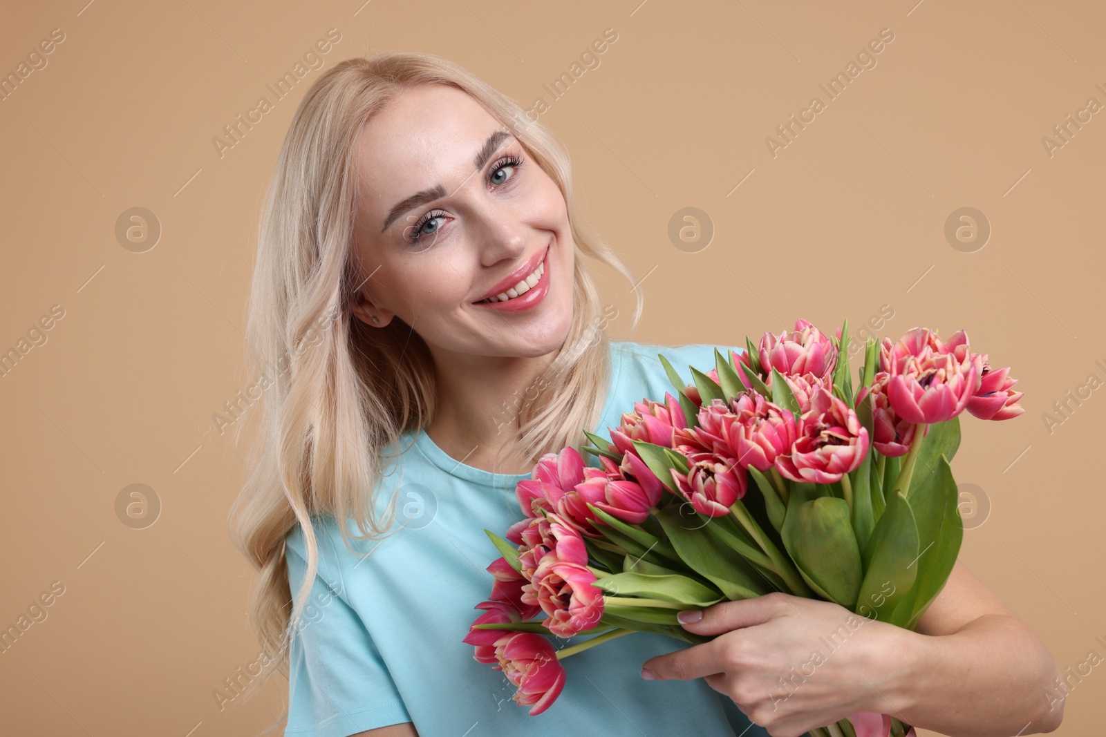 Photo of Happy young woman with beautiful bouquet on beige background