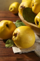 Photo of Tasty ripe quince fruits in bowl on wooden table, closeup