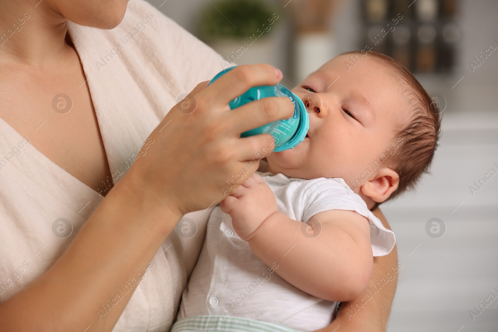 Photo of Mother feeding her cute child with infant formula indoors