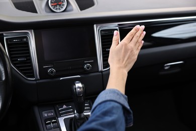 Woman checking air conditioner in her car, closeup