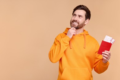 Photo of Smiling man with passport and tickets on beige background. Space for text