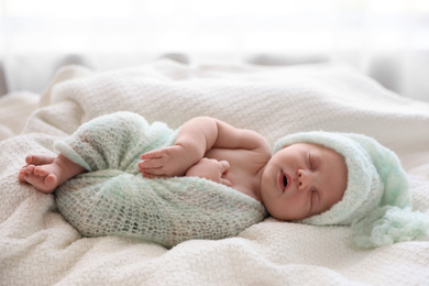 Cute newborn baby in warm hat sleeping on white plaid