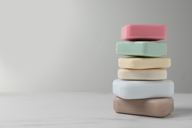 Photo of Stack of different soap bars on white marble table. Space for text