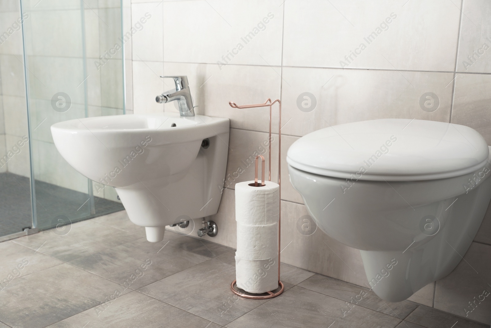 Photo of Holder with toilet paper rolls on floor in bathroom