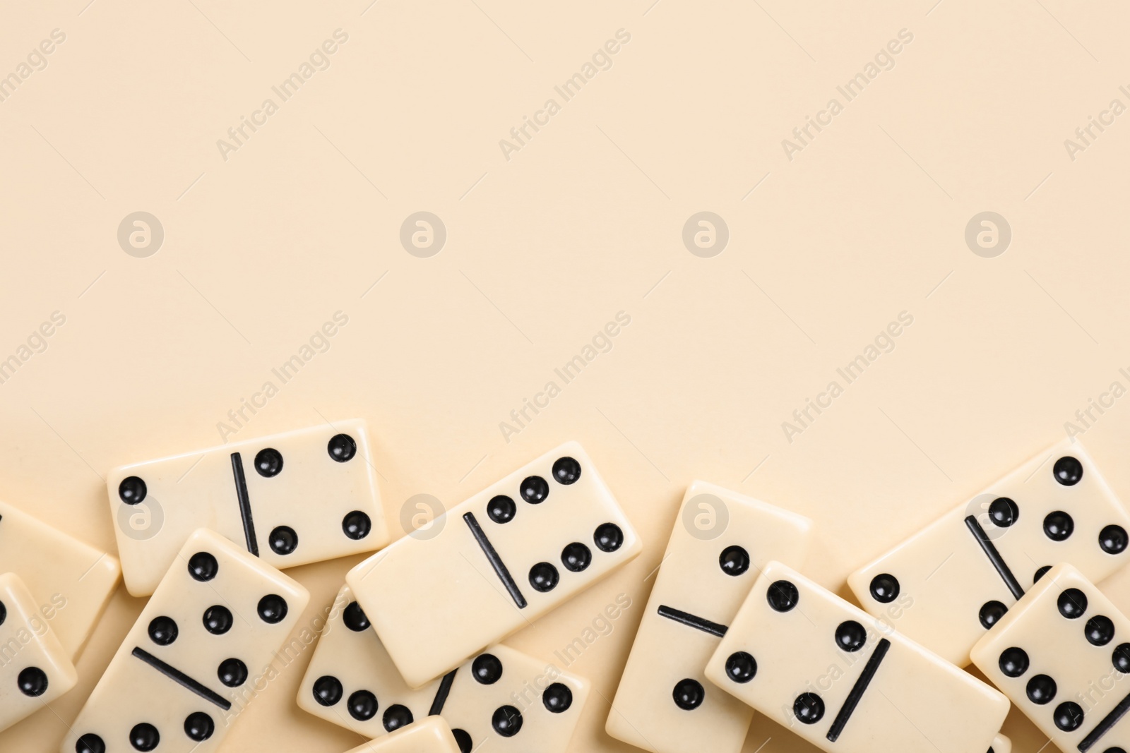 Photo of Classic domino tiles on beige background, flat lay. Space for text