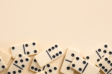 Classic domino tiles on beige background, flat lay. Space for text