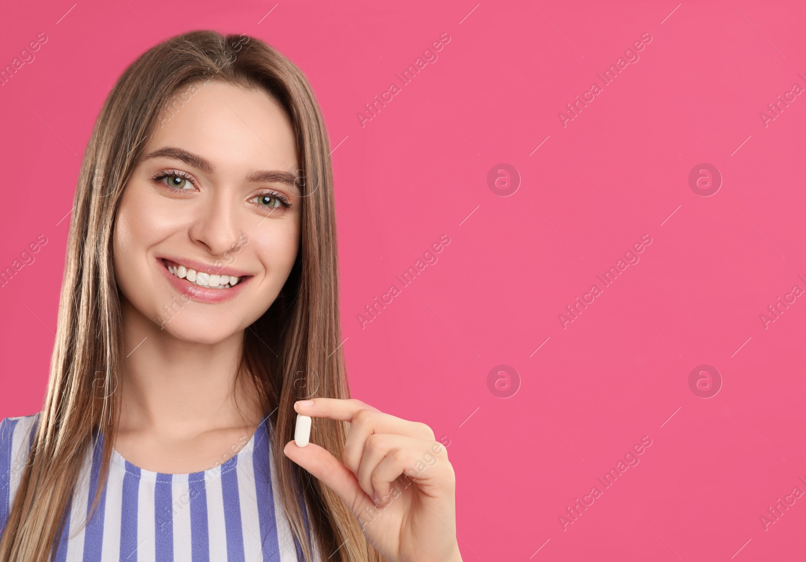 Photo of Young woman with vitamin pill on pink background. Space for text