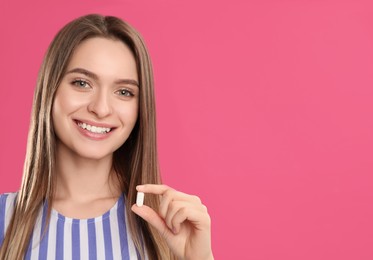 Photo of Young woman with vitamin pill on pink background. Space for text