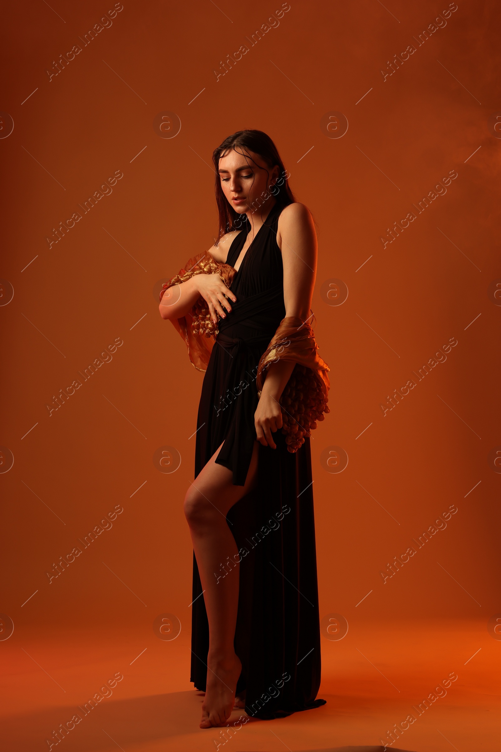 Photo of Beautiful woman in black dress and shawl posing on brown background