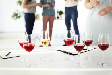 Photo of Glasses with delicious wine and blurred people on background