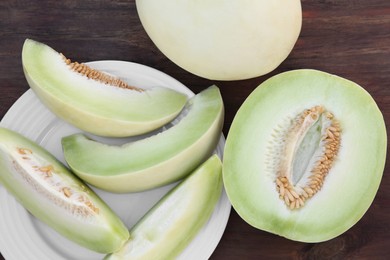 Tasty whole and cut ripe melons on wooden table, flat lay
