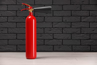 Photo of Fire extinguisher near grey brick wall, space for text