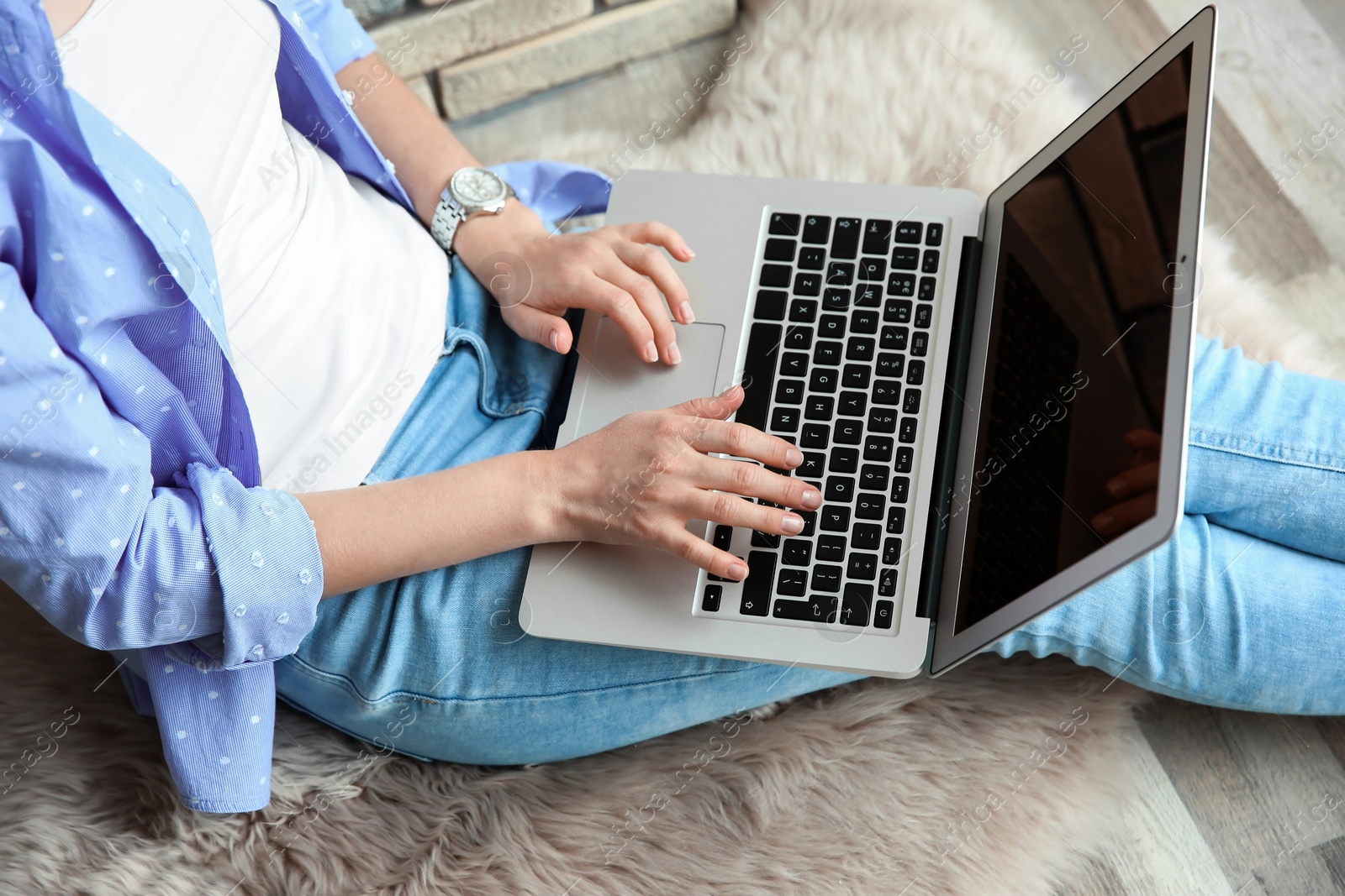 Photo of Young woman using laptop while sitting on floor indoors