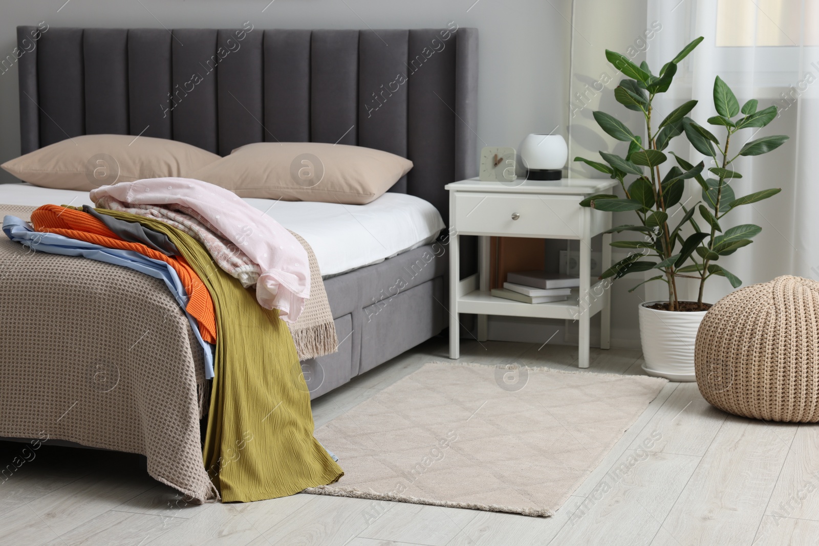 Photo of Pile of different clothes on bed at home