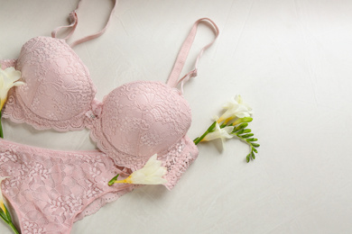 Photo of Sexy women's underwear and flowers on light background, flat lay