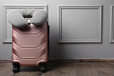 Photo of Striped travel pillow on suitcase near light wall indoors, space for text