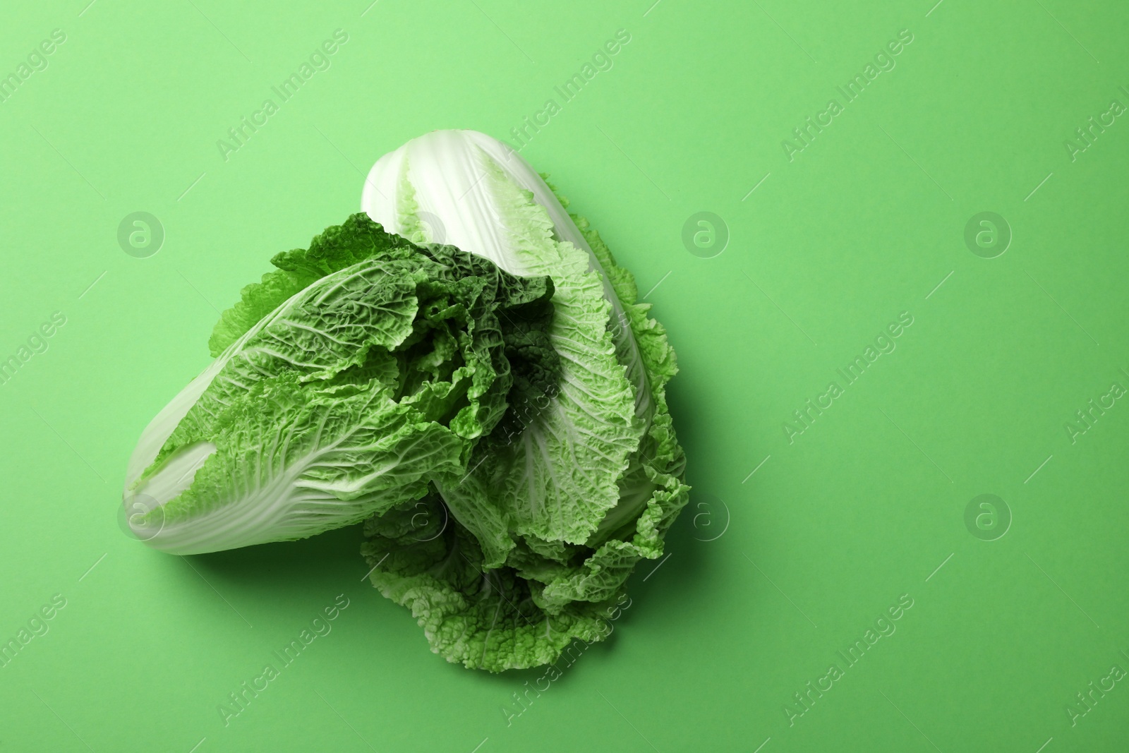 Photo of Fresh ripe Chinese cabbages on light green background, top view. Space for text