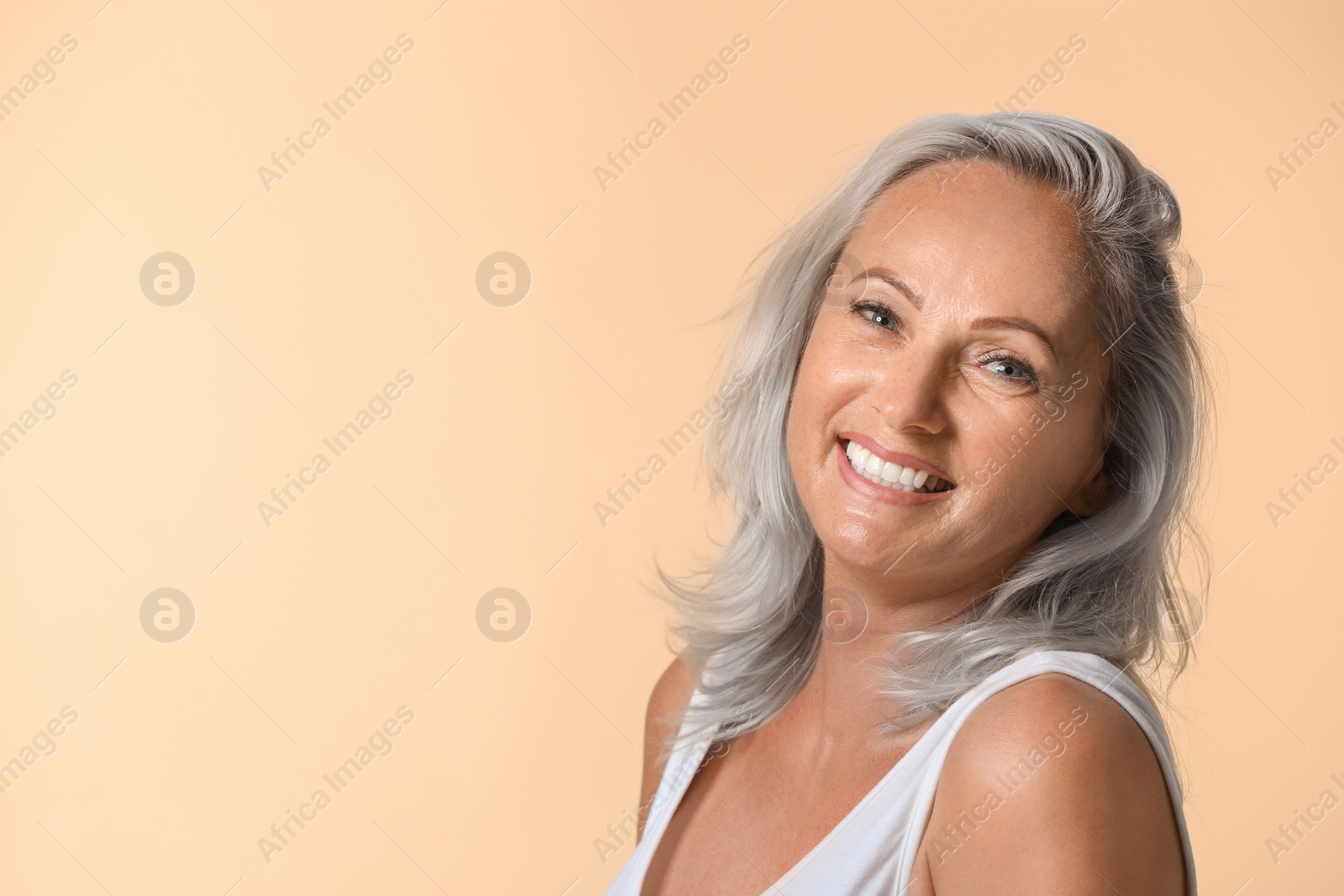 Image of Portrait of smiling woman with ash hair color on beige background. Space for text