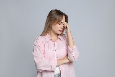 Photo of Young woman suffering from headache on light grey background