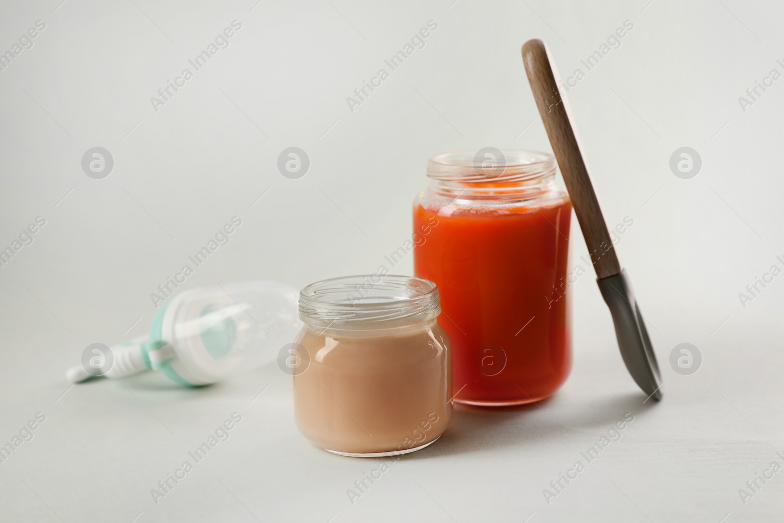 Photo of Healthy baby food, spoon and nibbler on white background