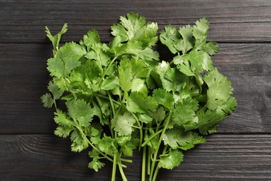 Photo of Bunch of fresh green cilantro on black wooden table, top view