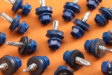 Blue self-tapping screws on orange background, closeup