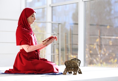 Photo of Muslim woman in hijab reading Koran indoors. Space for text