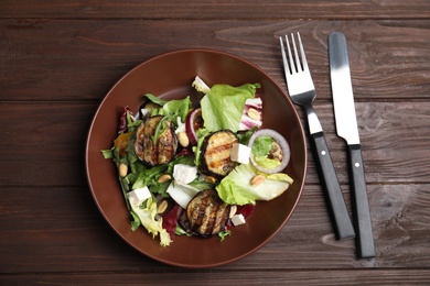 Photo of Delicious salad with roasted eggplant, feta cheese and arugula served on wooden table, flat lay