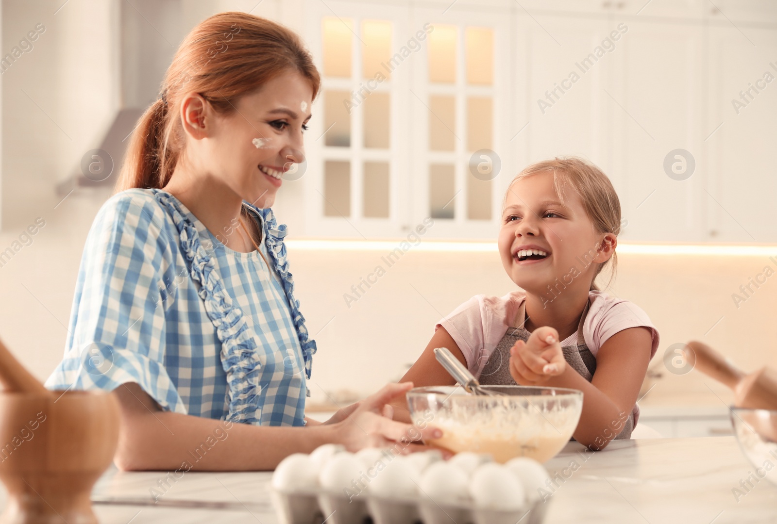 Photo of Mother and daughter making dough together in kitchen