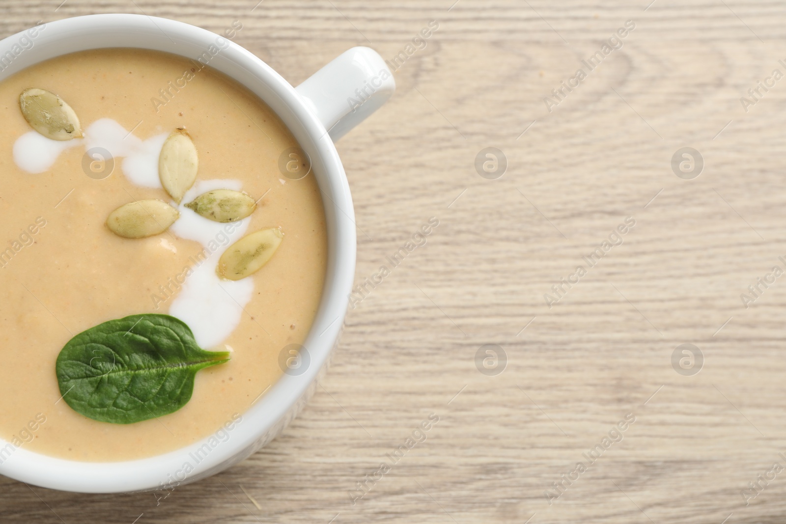 Photo of Healthy cream soup high in vegetable fats on wooden table, top view. Space for text