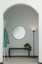 Photo of Stylish hallway interior with round mirror and bench